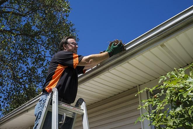 a repairman inspecting a clogged gutter for debris in Altadena, CA