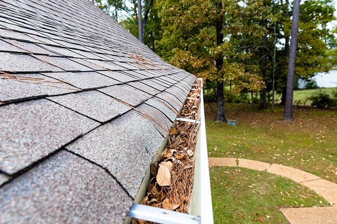 a man removing leaves and dirt from a gutter